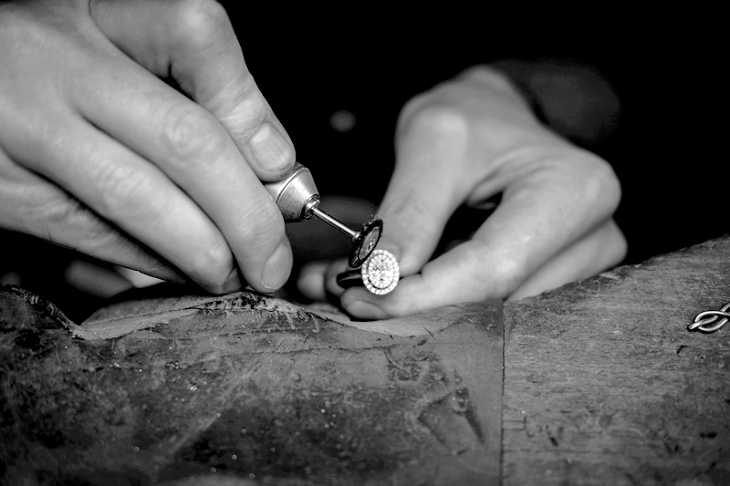Artisan joaillier en train de polir une bague en diamant sur son établi