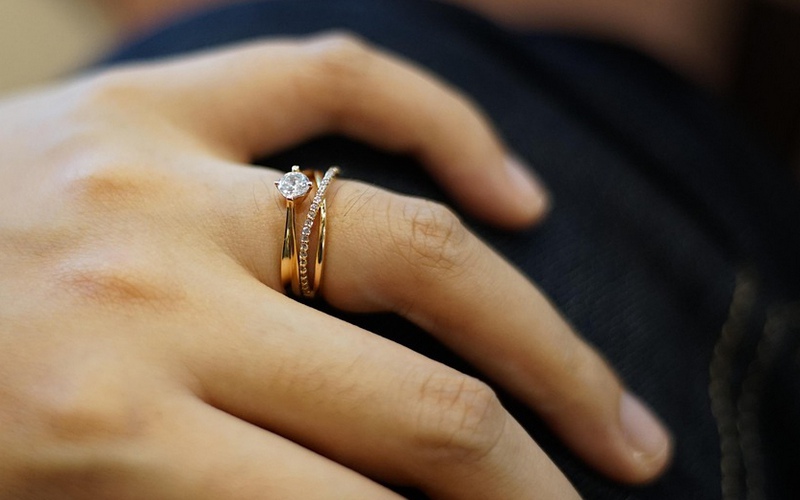 Alliance à double anneaux fins portée auprès d'une bagues de fiançailles solitaire en diamant