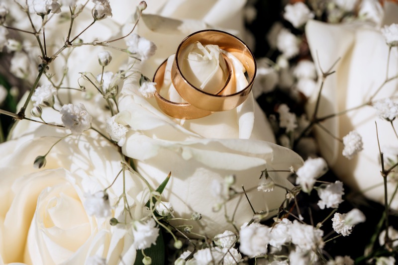 Ensemble d'alliances disposées près d'un bouquet de roses blanches