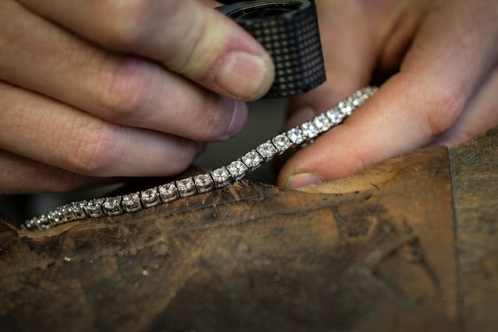 Artisan joaillier travaillant sur le sertissage et l'axage d'un bracelet tennis en diamant