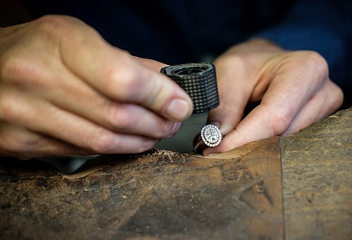 Expert joaillier diamantaire travaillant sur une bague de fiançailles pour femme en diamant
