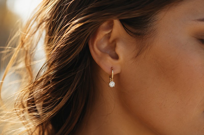 Boucles d'oreilles dormeuses en diamant et or jaune portées par une jeune femme aux cheveux longs, mettant en valeur le port de tête.