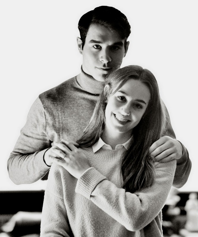 Jeune couple posant ensemble, la femme souriante montrant sa bague de fiançailles